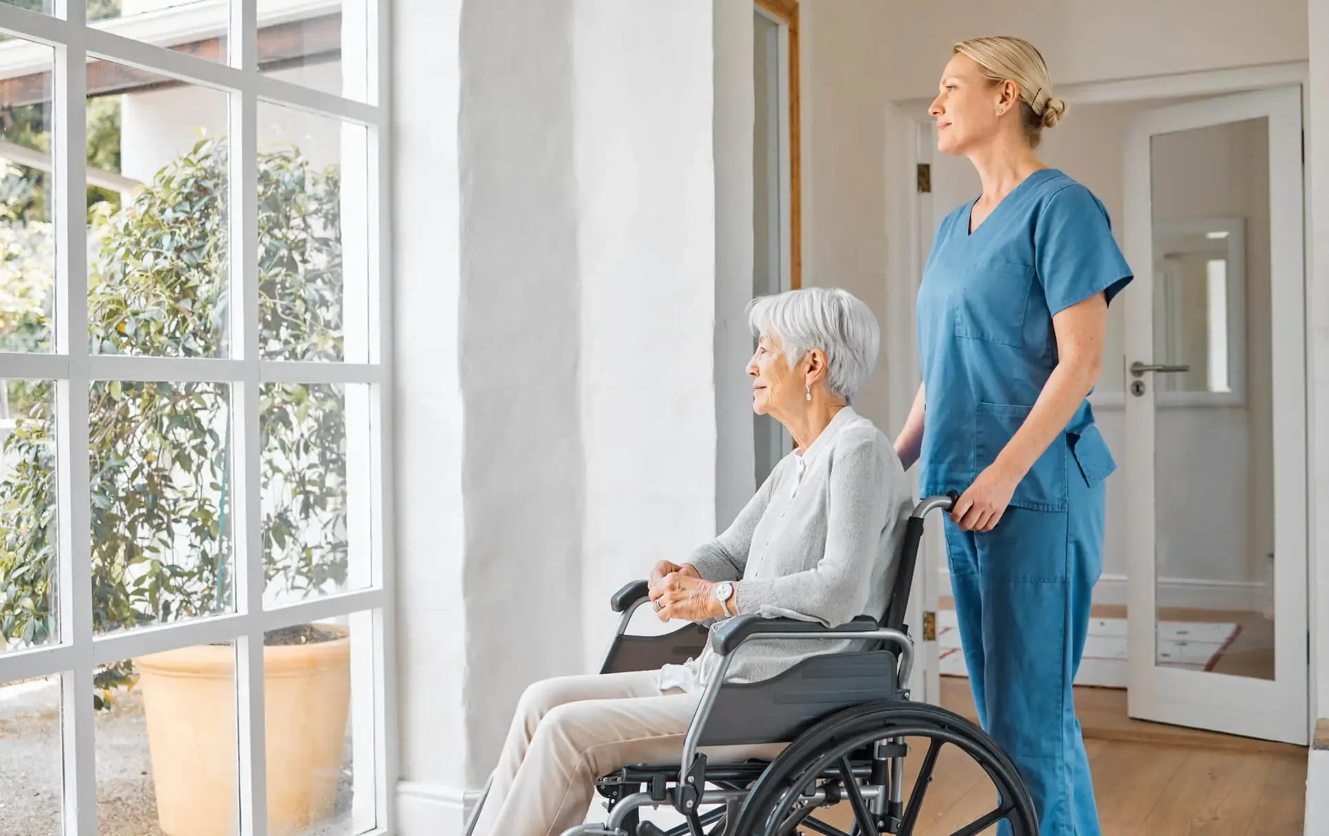 Pflegekraft kümmert sich um eine Seniorin in ihrer Wohnung
